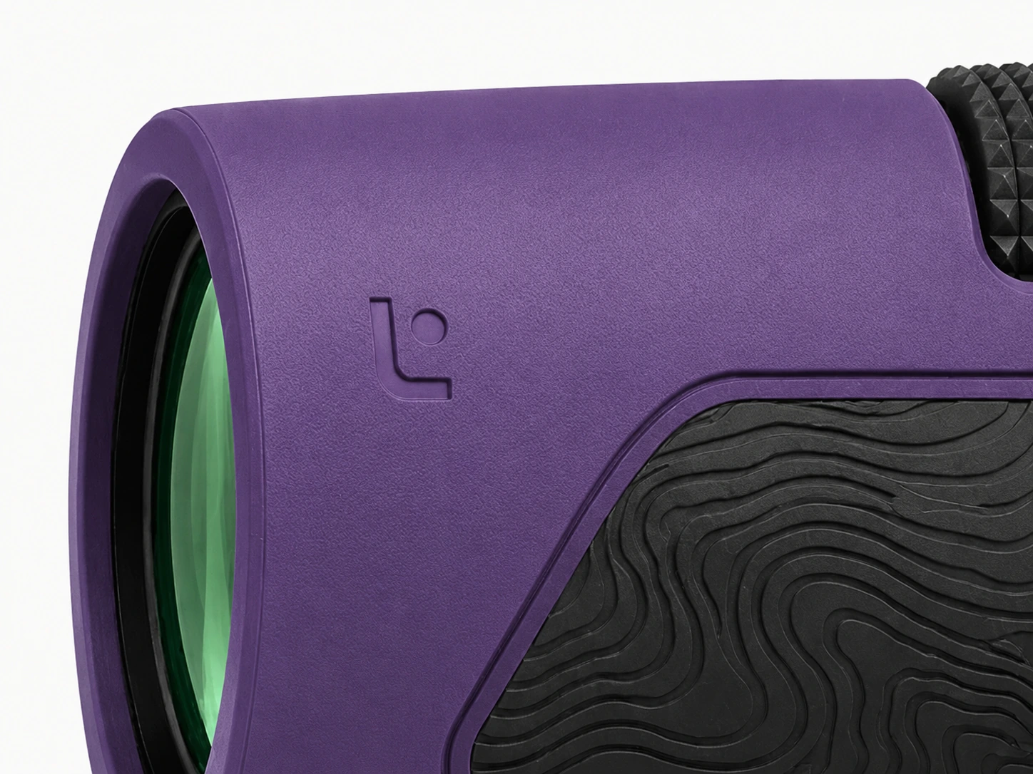 Close view of the debossed L monogram beside the green-coated objective lens